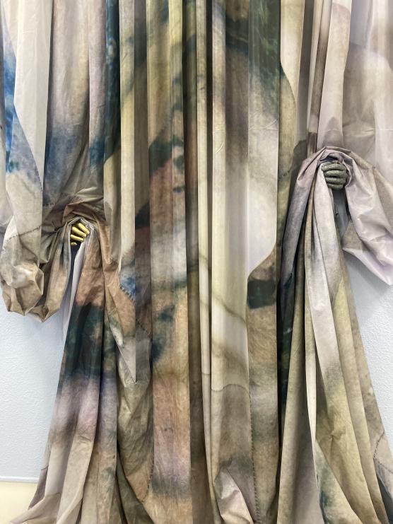 printed curtains held on wither side from behind by a cast hand