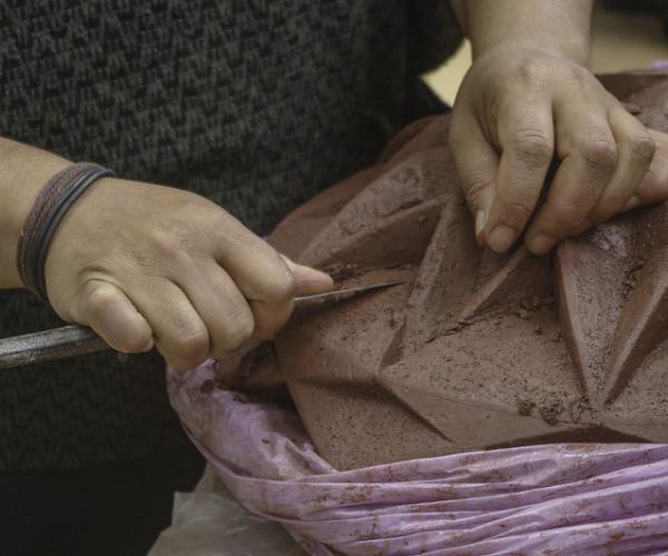 Halima working in her studio using clay