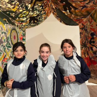Three students standing under a tent sculpture