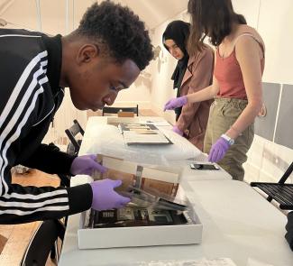 A student wearing purple gloves and handling archive documents