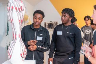 Two students looking at and discussing a red and white sculpture