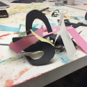 Image shows abstract sculpture made of black, pink and white paper