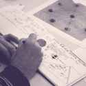 Image shows a hand writing in a notebook about a new game concept