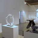 white exhibition room in museum with glass sculptures of different sizes on plinths and free standing