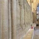 Installation view of "In the Shimmering Air" by Caro Williams at Wells Cathedral. Suspended brass text and sound notes shimmer in the North Quire Aisle.