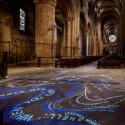 Text is projected in light onto the sandstone floor of Durham Cathedral 