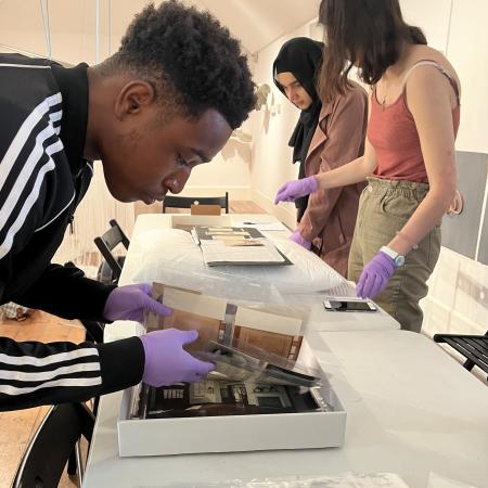 A student wearing purple gloves and looking at archival photographs