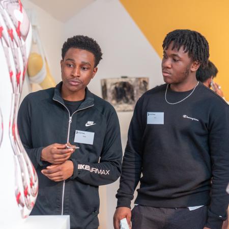 Two students viewing and discussing a white and red sculpture together